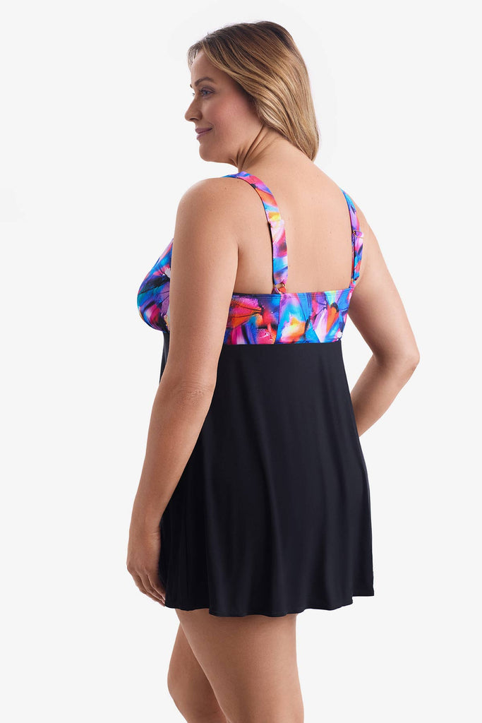 Woman faced left wearing a swim dress with a multicolored pattern on the bust