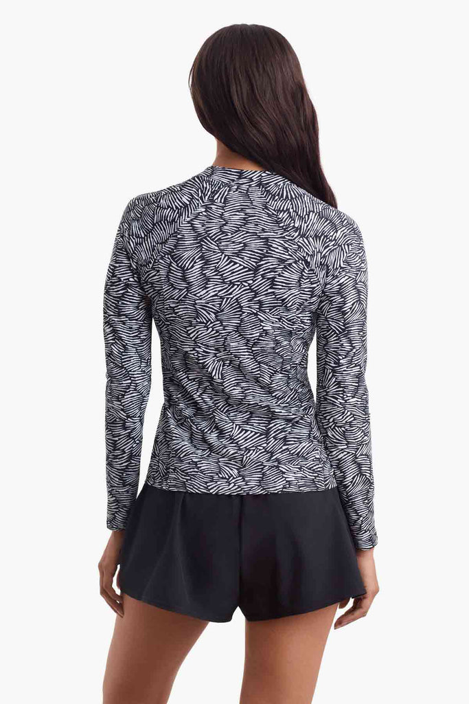 Woman faced away to show detail of the black and white print on the sun shirt