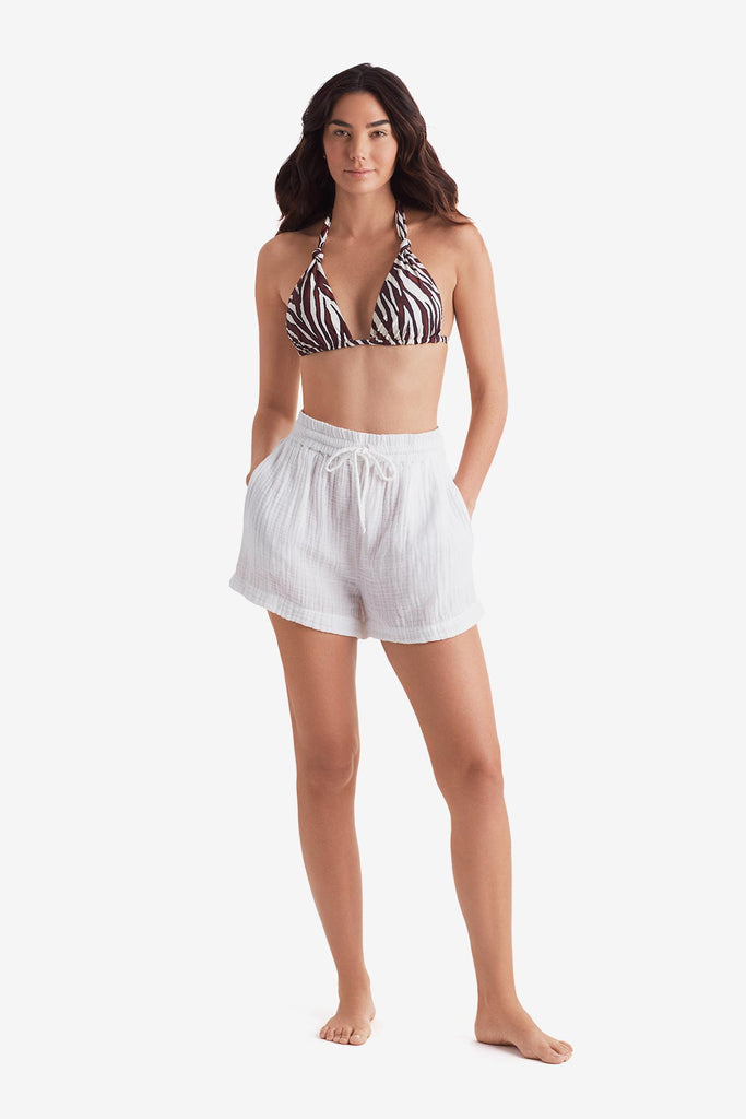 Woman wearing a zebra print bikini top with white beach shorts